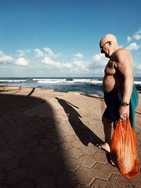 Full length of shirtless man standing on beach