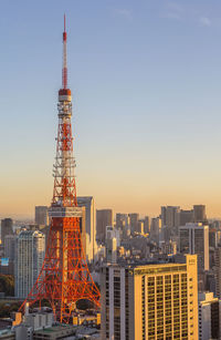 Tokyo tower and buildings in city against clear sky during sunset