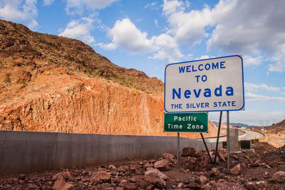 Road sign by mountains against sky