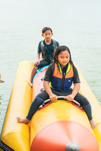 Portrait of smiling siblings sitting on boat