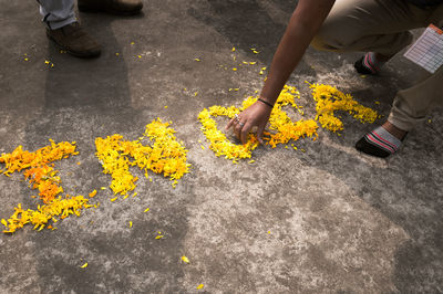 Low section of people pouring yellow flower on street