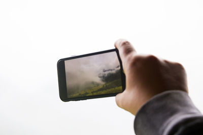 Midsection of person holding camera against white background