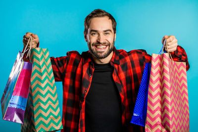 Portrait of smiling young man against blue wall