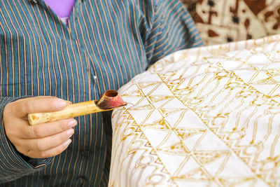 Midsection of woman making batik on textile