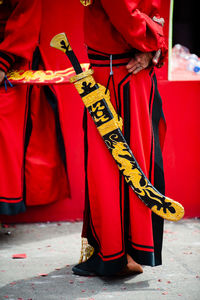 Midsection of man standing by red fire hydrant in city