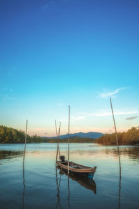 Sailboats moored in lake against blue sky