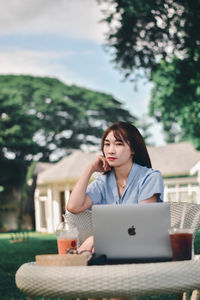 Woman using phone while sitting on table