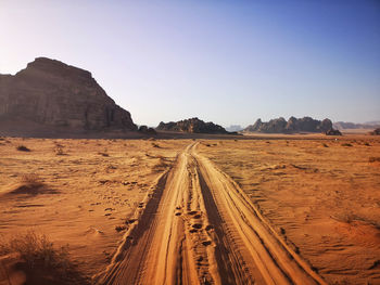 Panoramic view of landscape in the wadi rum with skidmarks in the desert against clear sky