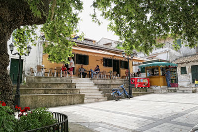 People on footpath by building in city