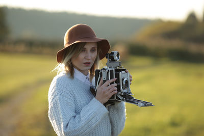 Young woman with camera standing on field
