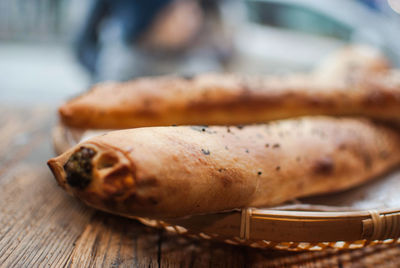 Close-up of breads in wicker plate on wooden table at bakery