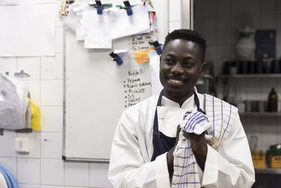 Smiling chef wiping hands while standing in commercial kitchen