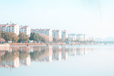 Reflection of city on water against clear sky