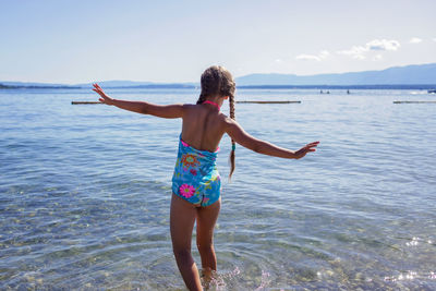 Girl goes into the water in sunlight, fun, happiness, summer vacations and travel, geneva lake