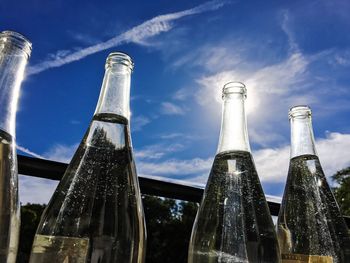 Low angle view of bottles against blue sky