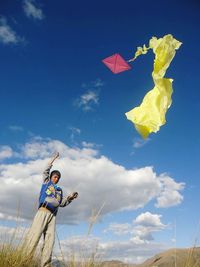 Low angle view of boy flying kite against sky