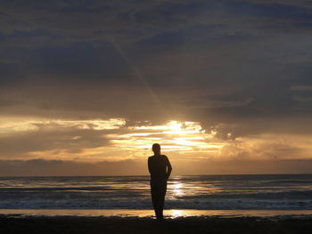 Silhouette of people on beach at sunset