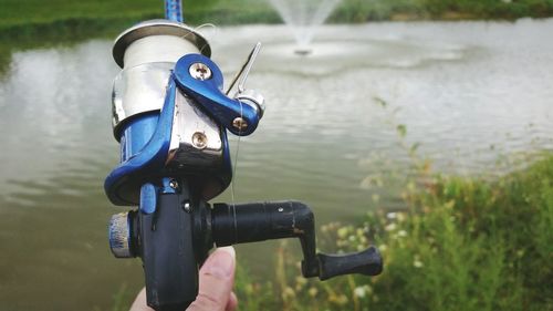 Close-up of hand holding fishing pole on lake