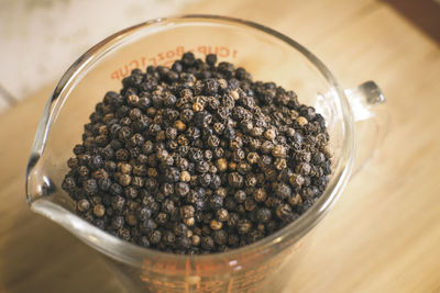 High angle view of black peppercorns in jar on table