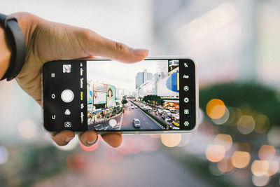 Close-up of hand holding mobile phone in city