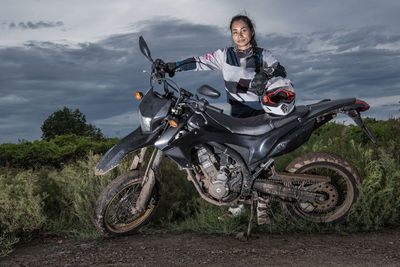 Woman posing behind her super moto style motorcycle on dirt road