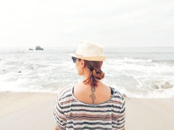 Rear view of woman looking at sea shore against sky