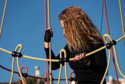 Beautiful woman standing on rope against sky