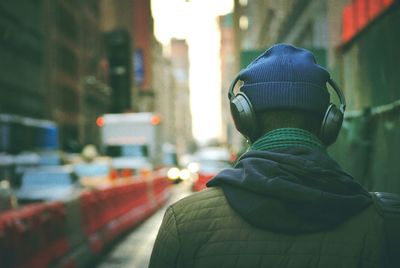 Rear view of man listening to music in street