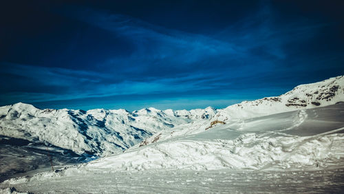 Scenic view of snowcapped mountains against blue sky