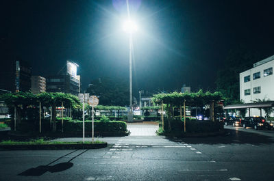 Illuminated road by city against sky at night