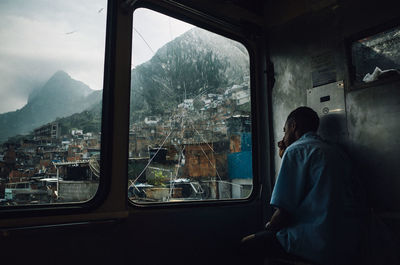 Rear view of man looking through window