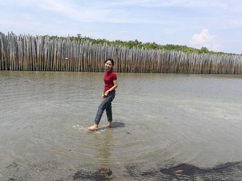 Full length of boy standing in water against sky