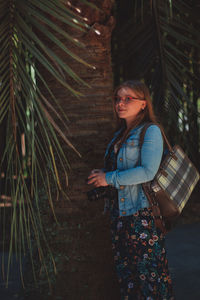 Portrait of smiling young woman standing against trees