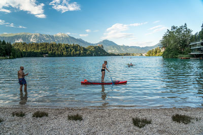 People on lake against sky