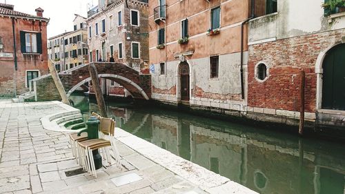 Arch bridge over canal amidst buildings in city