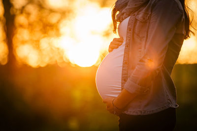 Midsection of pregnant woman standing at forest