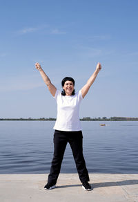 Full length of young man standing in sea against sky