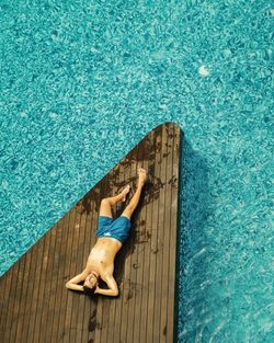 High angle view of shirtless man relaxing at poolside