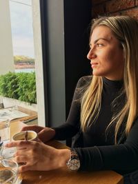 Woman having coffee while looking through window