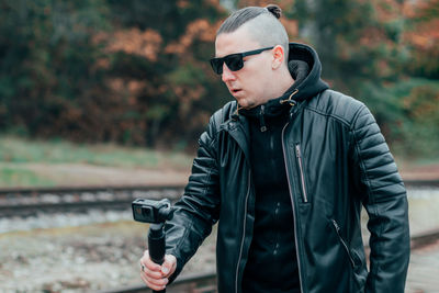 Young man wearing sunglasses filming with video camera