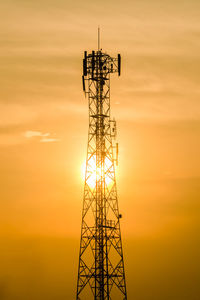 Low angle view of silhouette communications tower against sky during sunset