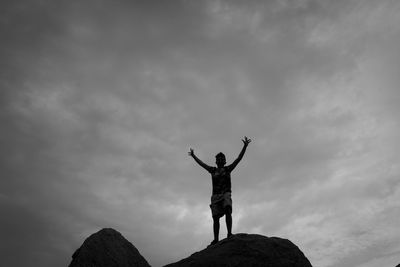 Low angle view of silhouette person standing on rock