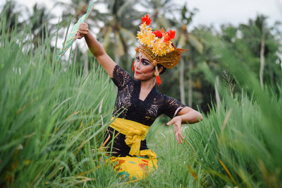 Woman in traditional clothing dancing on grass against sky
