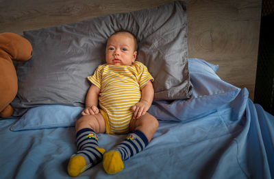 Full length of cute baby relaxing on bed at home