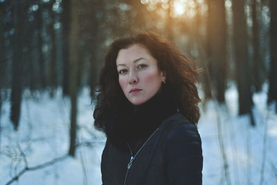 Portrait of young woman standing in forest during winter