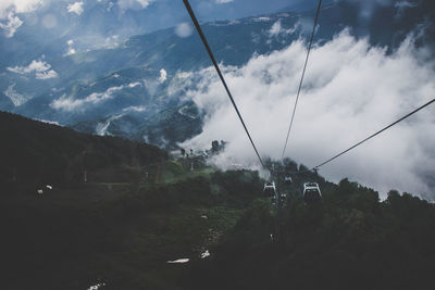 Overhead cable car over mountains against sky