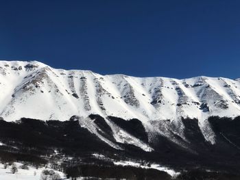 Snowcapped mountains against clear blue sky