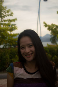 Portrait of young woman standing against lake during sunset