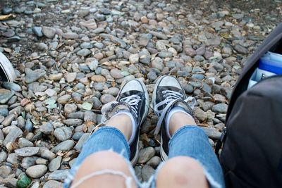 Low section of woman sitting on pebbles