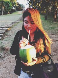 Smiling young woman drinking coconut water from straw